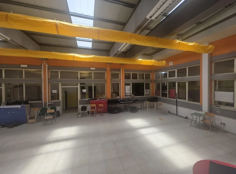 Canali tessili gialli della climatizzazione sotto i lucernari dell'aula magna scolastica
