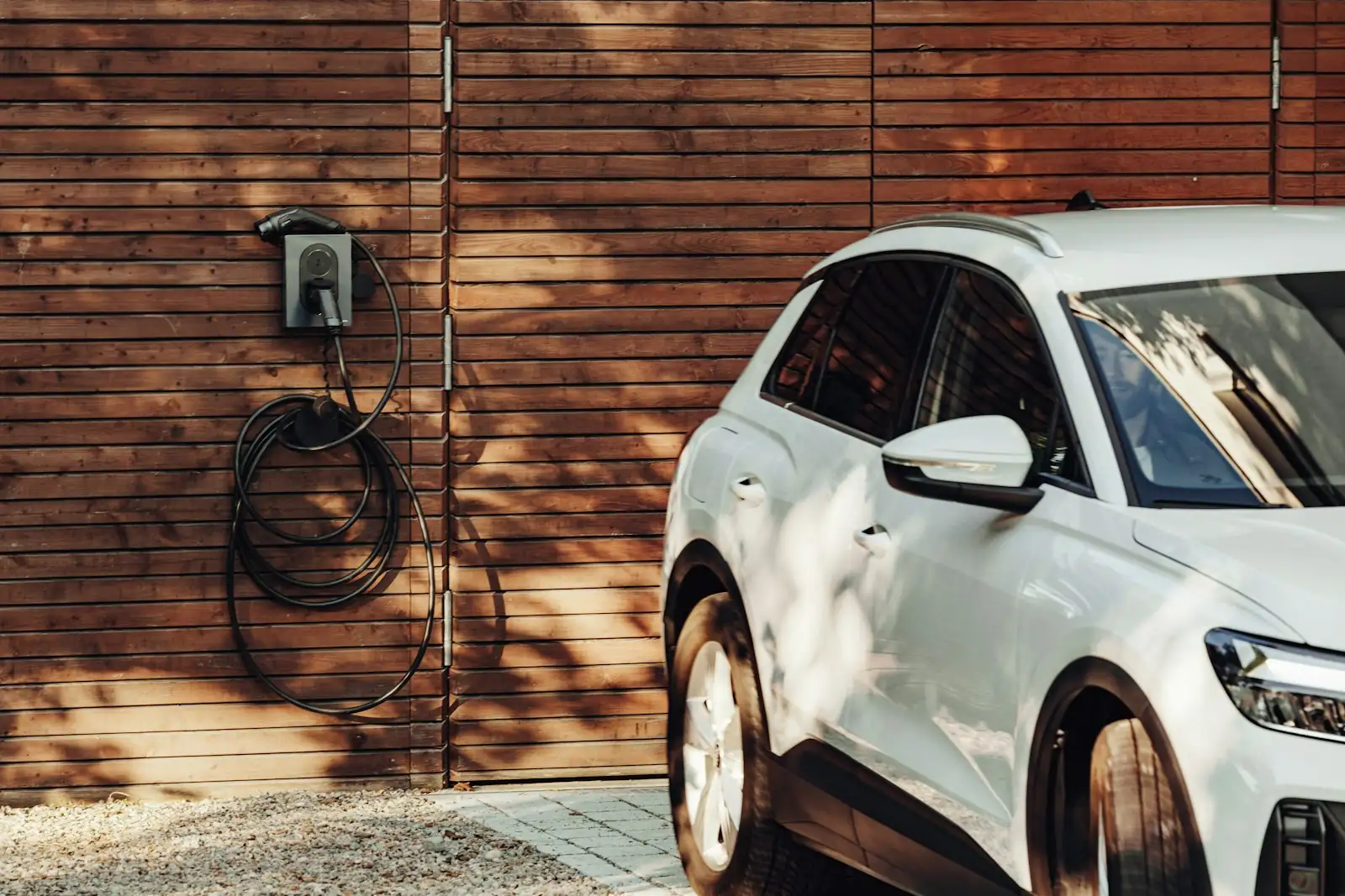Wallbox sulla parete esterna di una casa con un'auto elettrica parcheggiata accanto