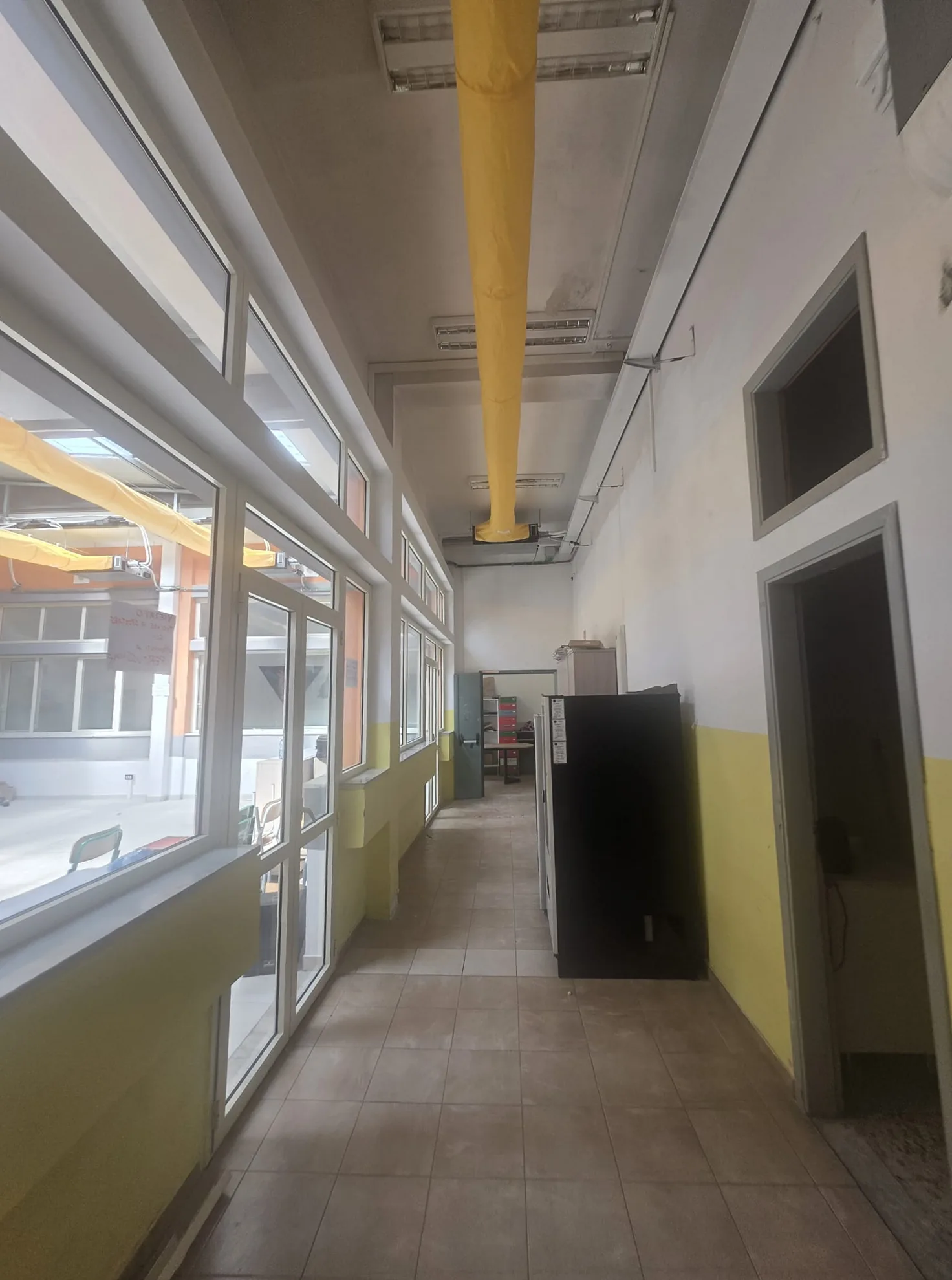 Canale di climatizzazione lungo il soffitto di un corridoio della scuola Brugnano, affacciato sulle vetrate del patio interno