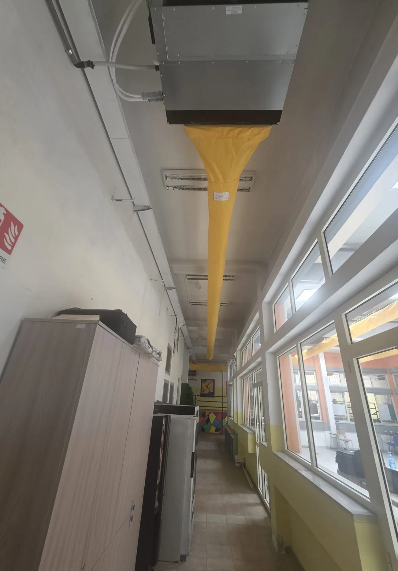 Unità canalizzabile installata a soffitto in un corridoio della scuola Brugnano, con il canale tessile in uscita