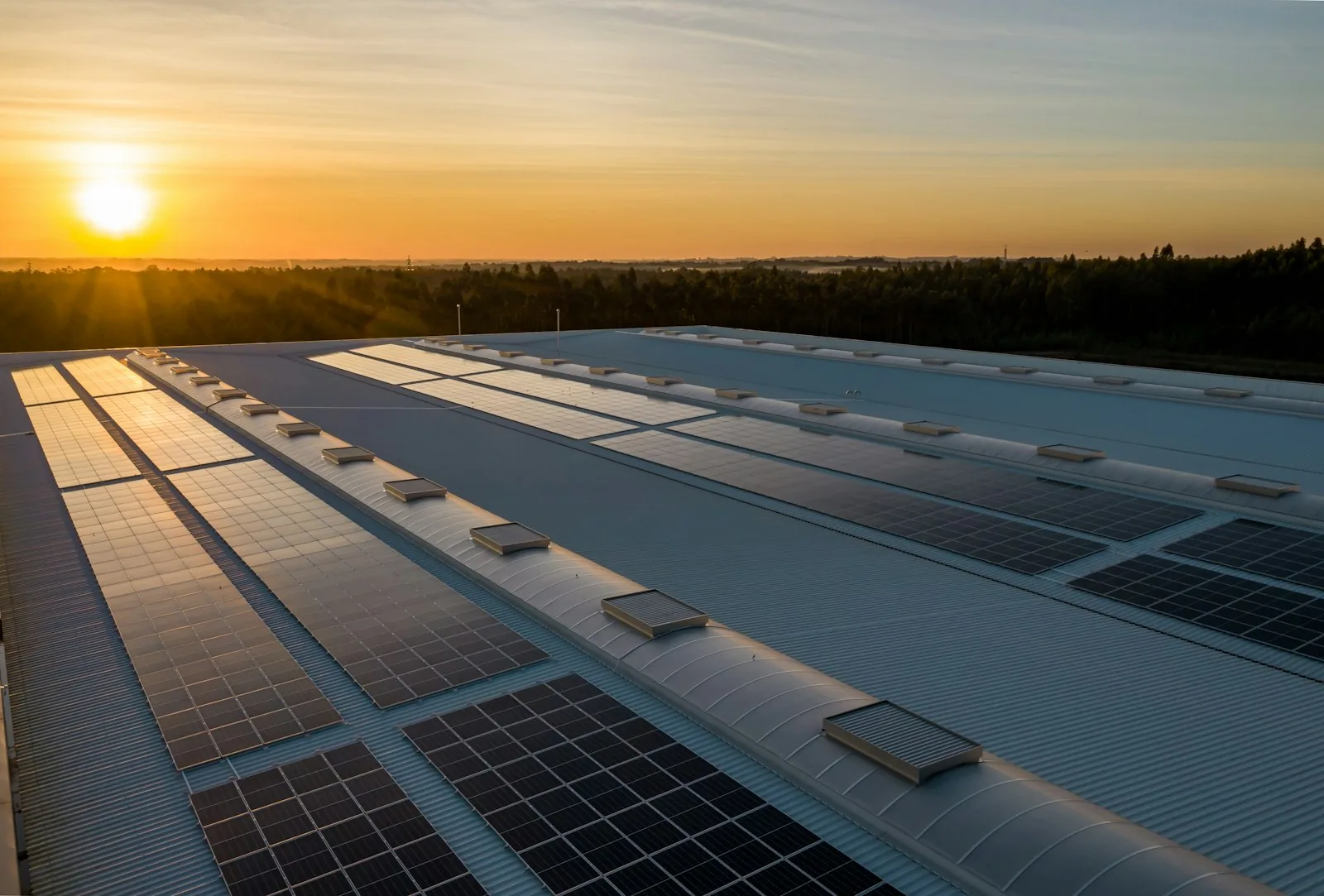 Impianto fotovoltaico installato sulla copertura di un capannone industriale al tramonto