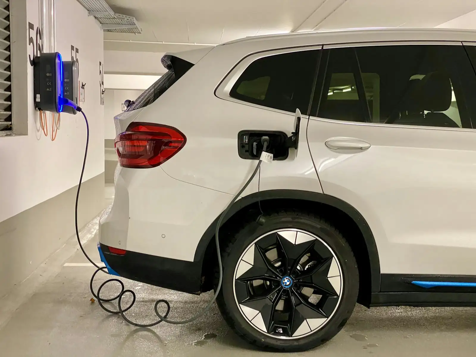 Auto elettrica in ricarica da una wallbox a parete in un garage