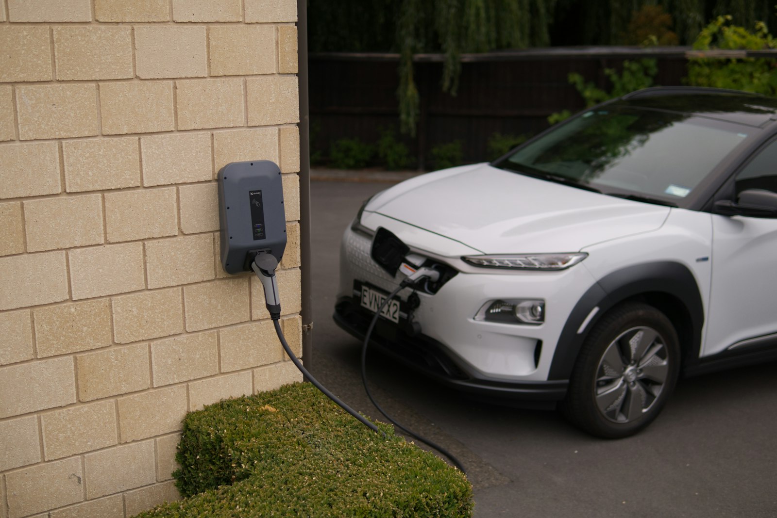 Wallbox a parete con un'auto elettrica in ricarica nel cortile